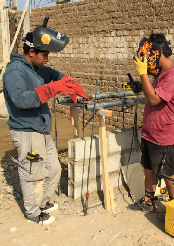 Jhikson explaining how to weld to his friend during the La Rampa's skatepark construction in Peru