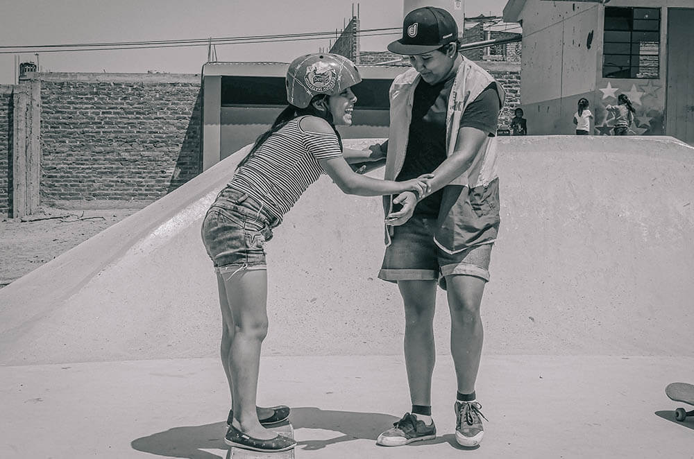 Leila helping a girl skateboarding in Alto Trujillo, Peru