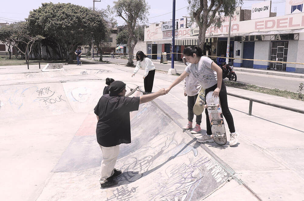 A fist-bump during a skateboarding class with CJF Peru