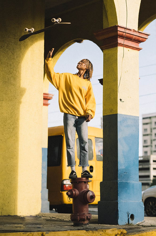 Kayla throwing a skateboard in the air in Jamaica