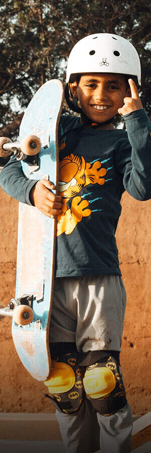 Boy at the Fiers et Forts skatepark in Morocco smiling with a skatebaord in his hand
