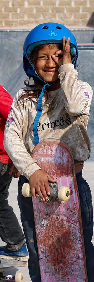 Girl in Cerrito's skatepark in Peru smiling with her skateboard.